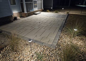 Beautiful paver patio with grey and beige pavers, decorative stone, and landscape lighting / low voltage lighting, techo bloc, belgard